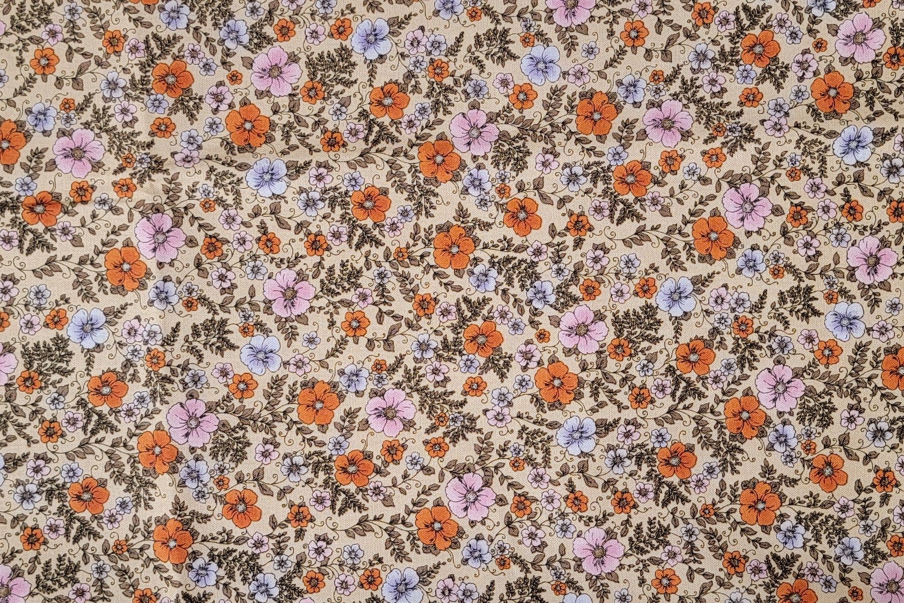 A close-up of a vintage floral fabric pattern featuring orange, purple, and pink flowers with brown leaves on a beige background.