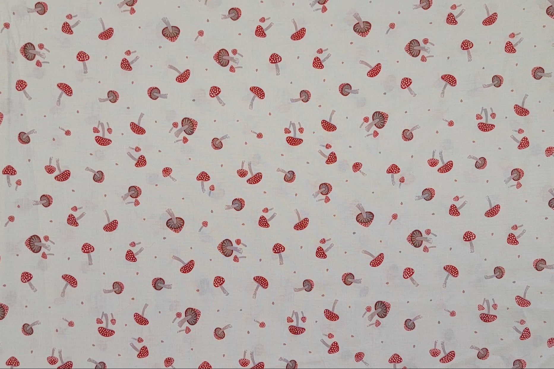 A close-up of a fabric pattern featuring small red and gray mushrooms scattered across a light off-white background.