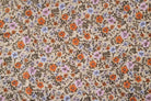 A close-up of a vintage floral fabric pattern featuring orange, purple, and pink flowers with brown leaves on a beige background.