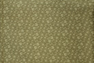 A close-up of a fabric surface with a small repeating floral or paisley-like pattern in muted olive green.