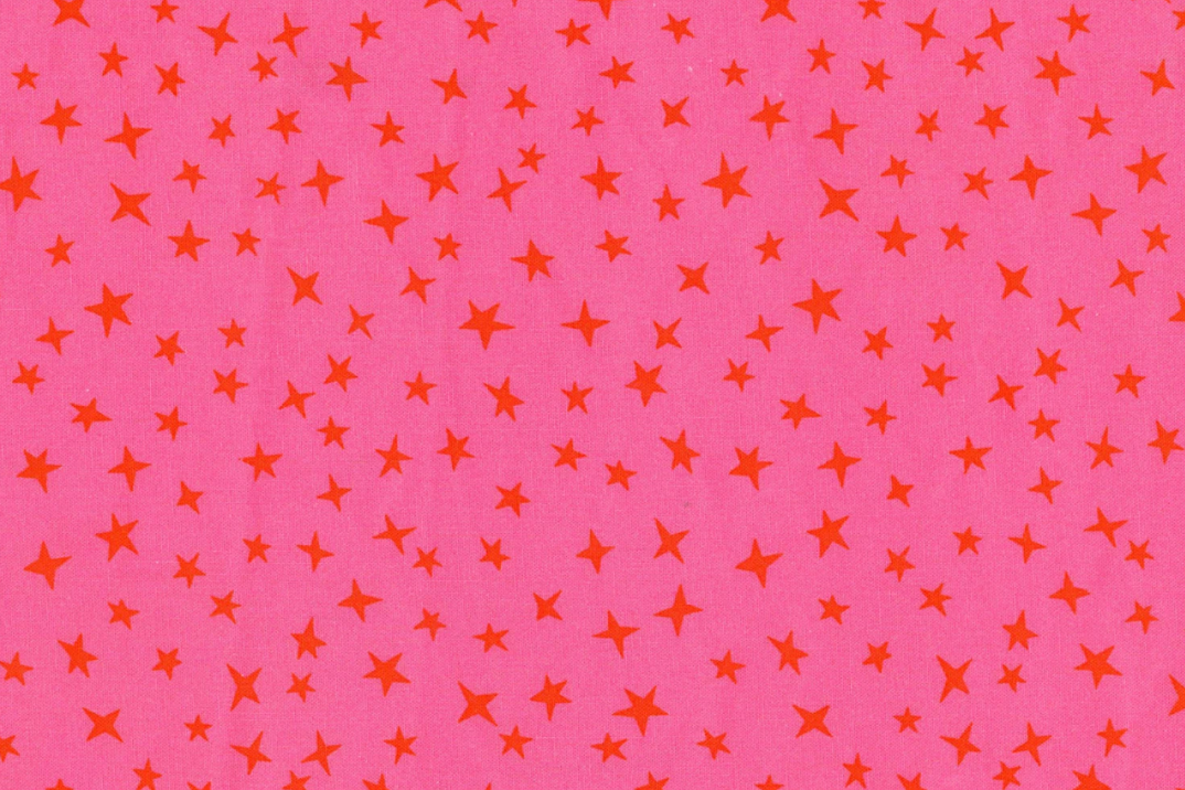 A close-up of a pink fabric or material with an allover pattern of small orange stars in varying sizes.