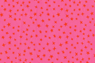 A close-up of a pink fabric or material with an allover pattern of small orange stars in varying sizes.
