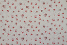 A close-up of a fabric pattern featuring small red and gray mushrooms scattered across a light off-white background.