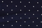 A close-up of a navy blue fabric with a repeating pattern of small white polka dots.