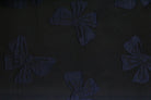 A close-up of a dark fabric with a repeating bow pattern.