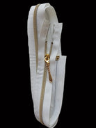 A white textured zipper tape strip with a gold-toned metal zipper and pull tab, photographed against a plain light gray background.